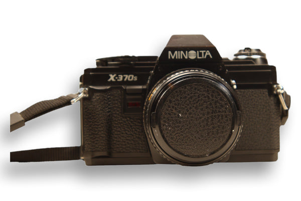 Minolta X-370S film camera with lens cap attached, protecting the Minolta Rokkor-X 50mm f/1.7 lens. A reliable SLR for film photography enthusiasts.