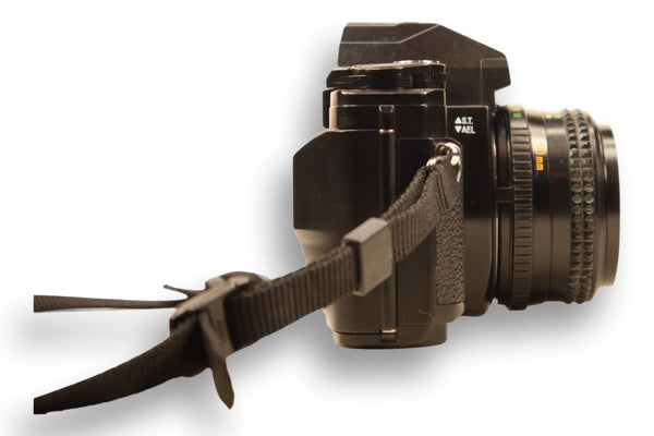 Side view of Minolta X-370S film camera with strap, showing the textured grip and lens focus markings. A great choice for manual photography.