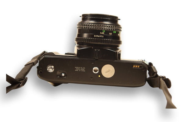 Bottom view of Minolta X-370S film camera, showing battery compartment and tripod mount. A durable and reliable choice for film photographers.