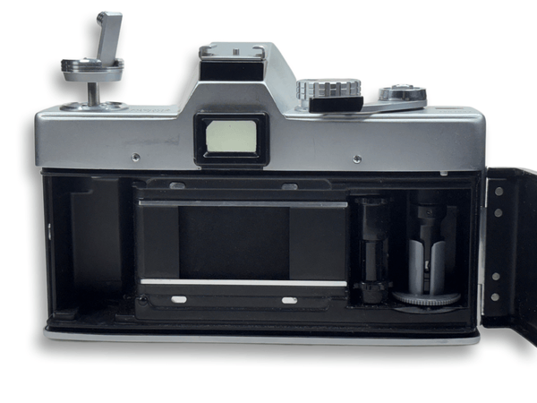 Vintage camera with open back showing film cassette on a white background