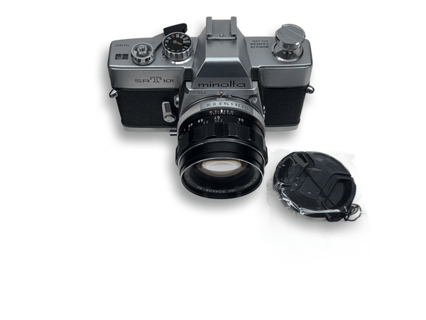 Vintage camera with lens, strap, and plastic bag on a white surface